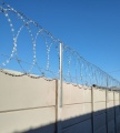 Zasieki płaskie na ogrodzeniu betonowym z wysięgnikami prostymi